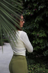 Woman outdoors in olive INGE Shorts and a cream Sheer Wrap Top, back view